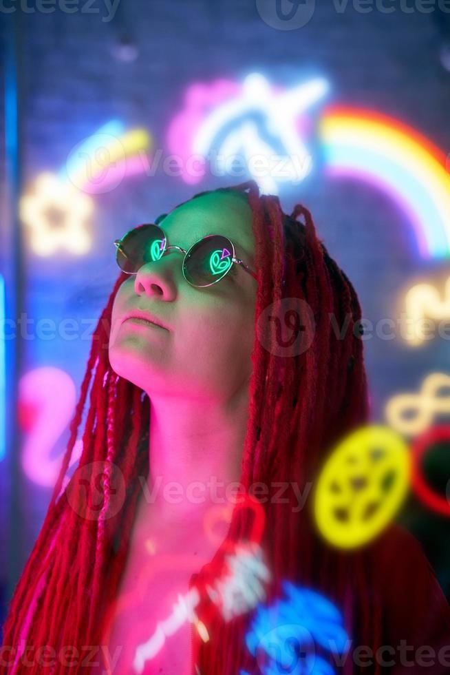 mädchen in neonlichtern, schöne frau in sonnenbrille, mit rosa haaren, mit dreadlocks zöpfen foto