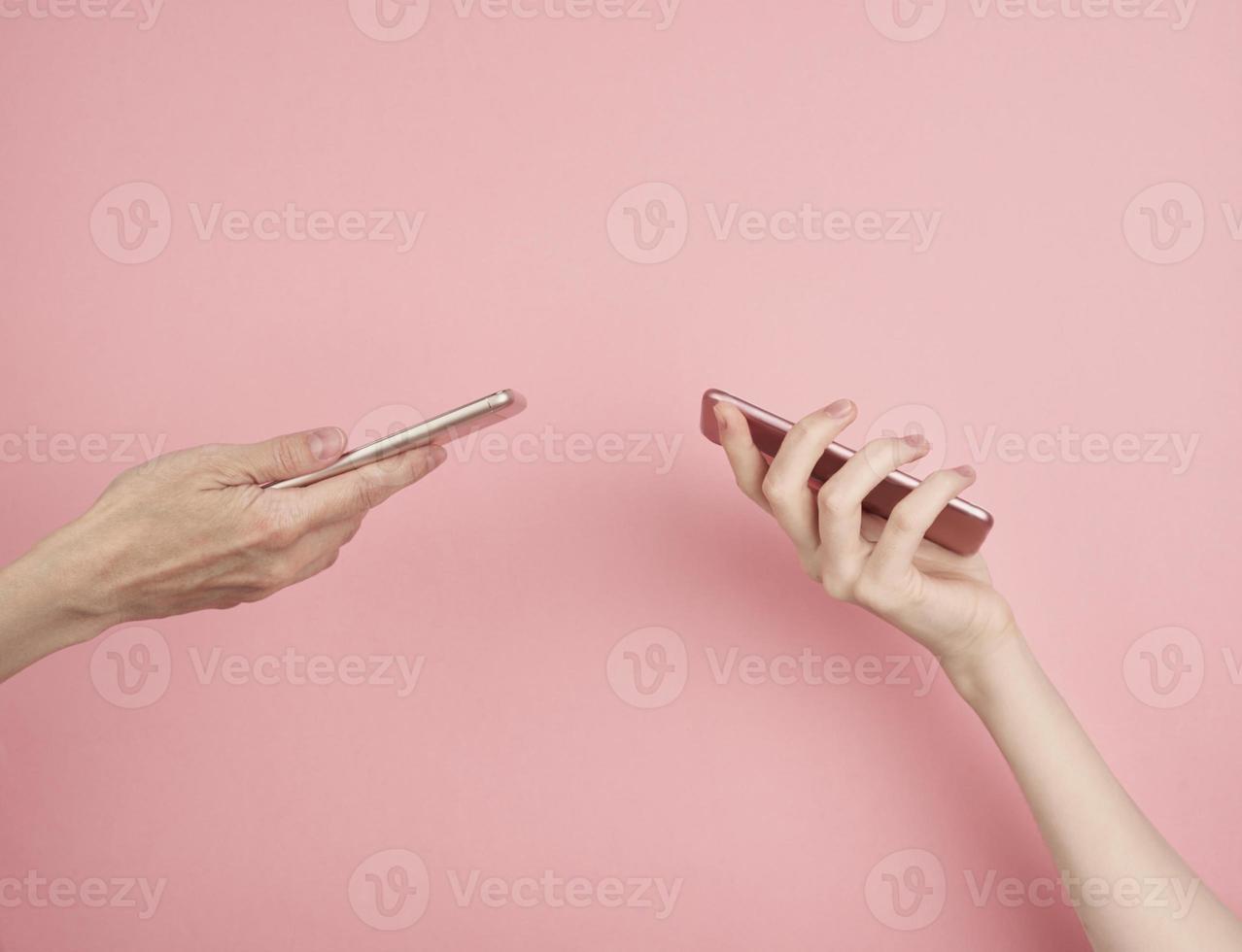 zwei frauen halten telefon auf pastellrosa hintergrundkopienraum seitenansicht foto