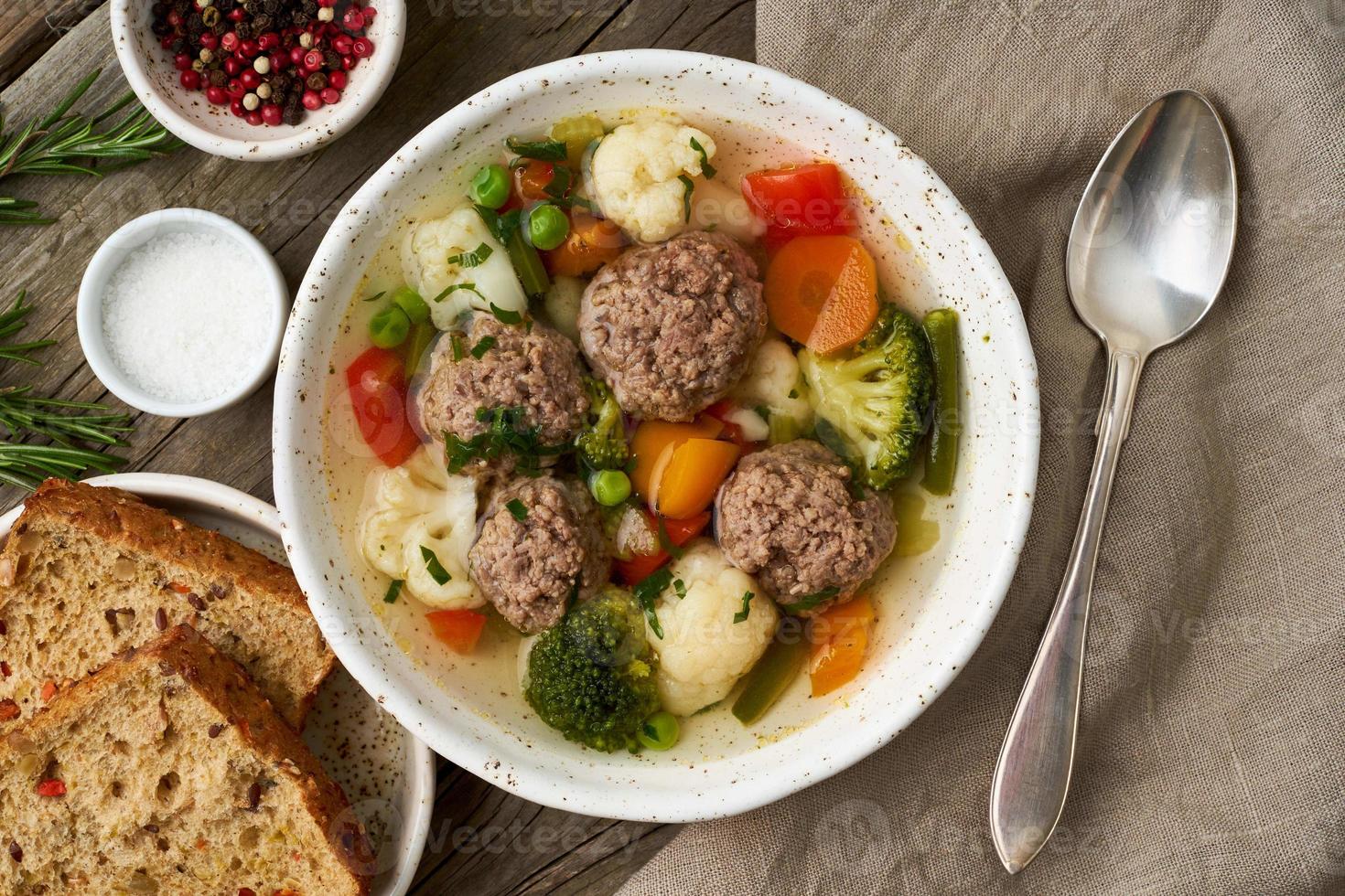 Frikadellensuppe in weißer Platte auf altem rustikalem grauem Holztisch, Draufsicht foto