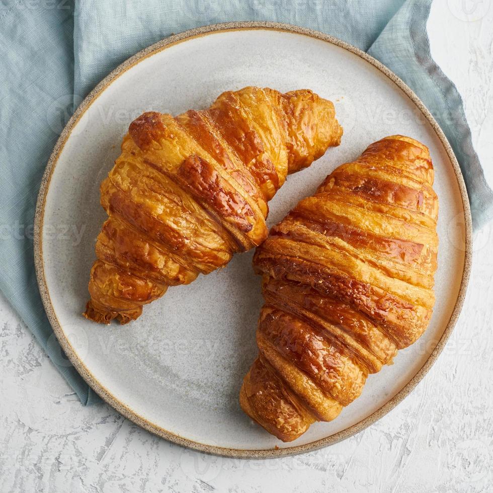 zwei leckere croissants auf teller und heißes getränk im becher. morgens französisches frühstück foto