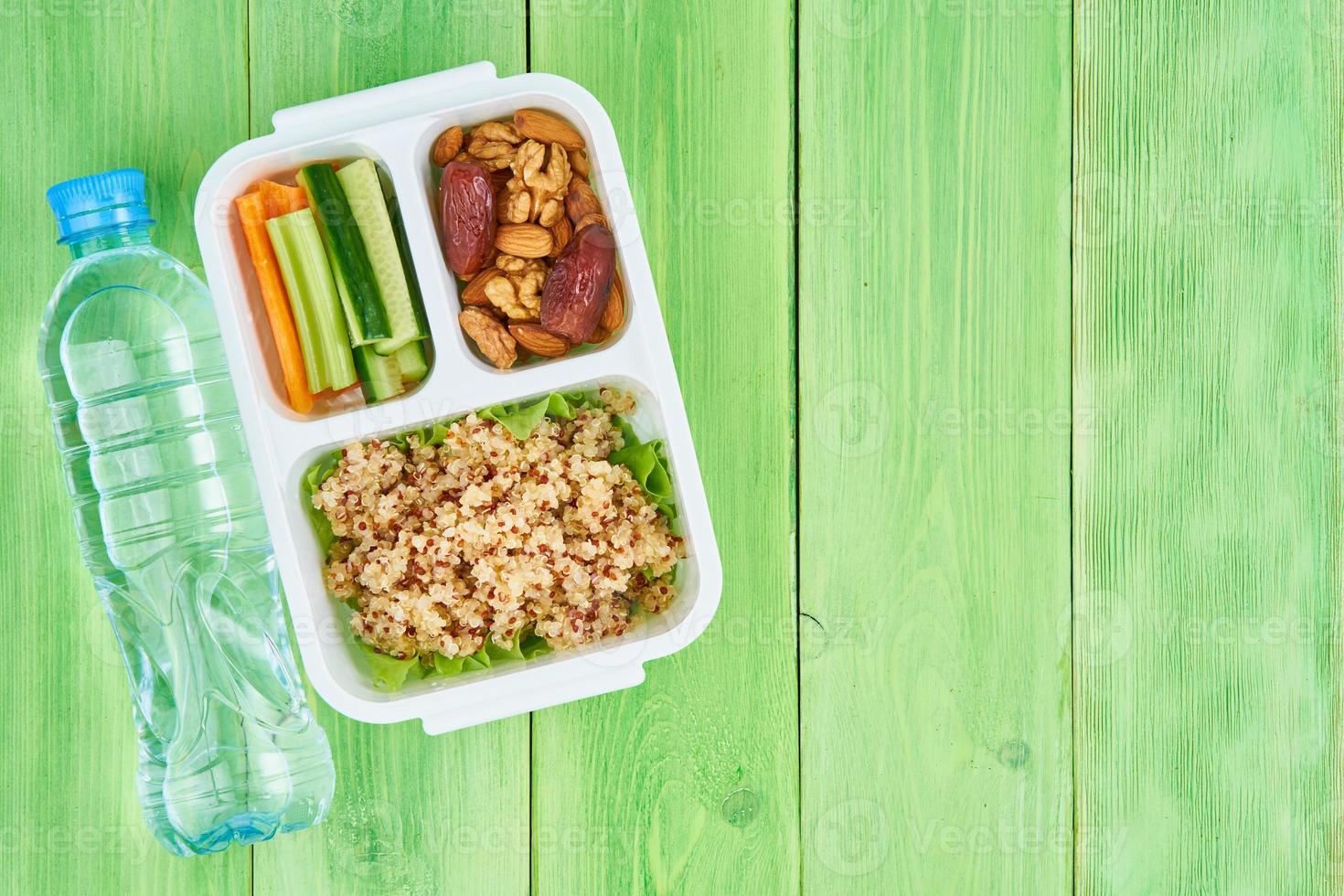 vegane Lunchbox, Wasser in der Flasche, grüner Hintergrund, Kopierraum. foto