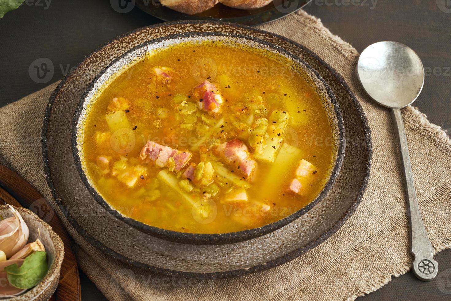 heiße Wintersuppe mit gehackten grünen Erbsen, Schweinefleisch, Speck, geräuchert auf dunkelbraunem Holztisch. köstliche appetitliche fettreiche Suppe. foto