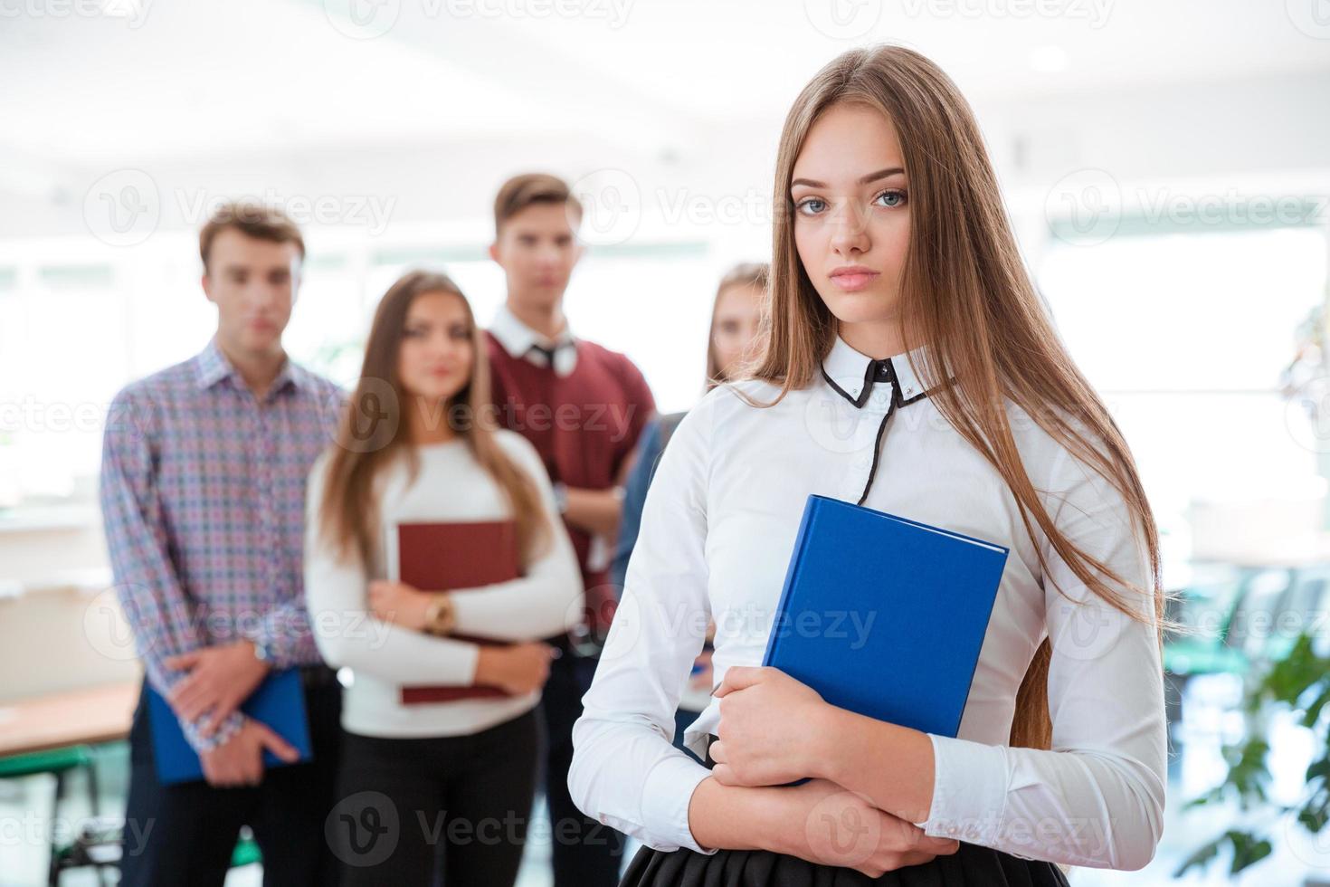 Studentin, die mit Klassenkameraden auf Hintergrund steht foto