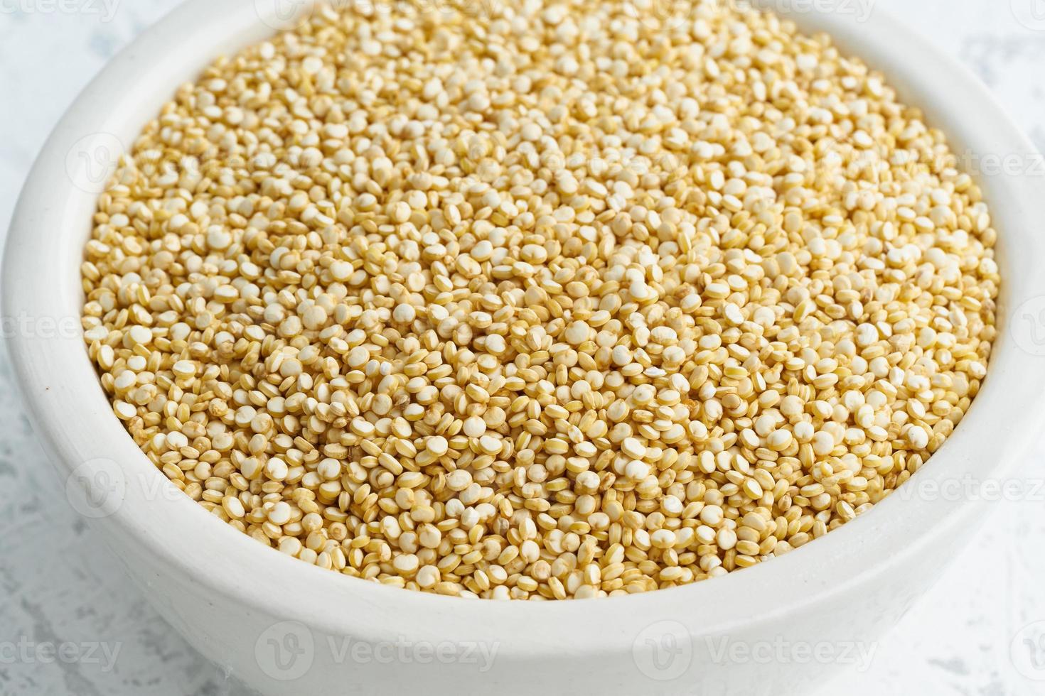 Quinoasamen in weißer Schüssel auf weißem Hintergrund. getrocknetes Getreide in der Tasse, veganes Essen, Fodmap-Diät foto