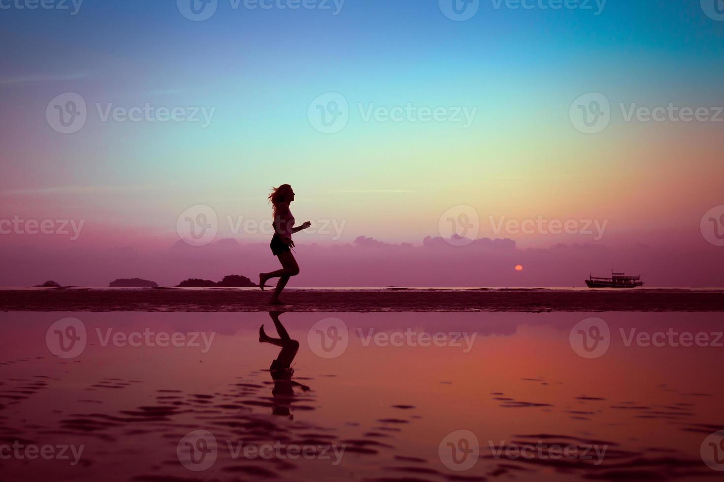 weibliche Läuferin am Strand bei Sonnenuntergang foto