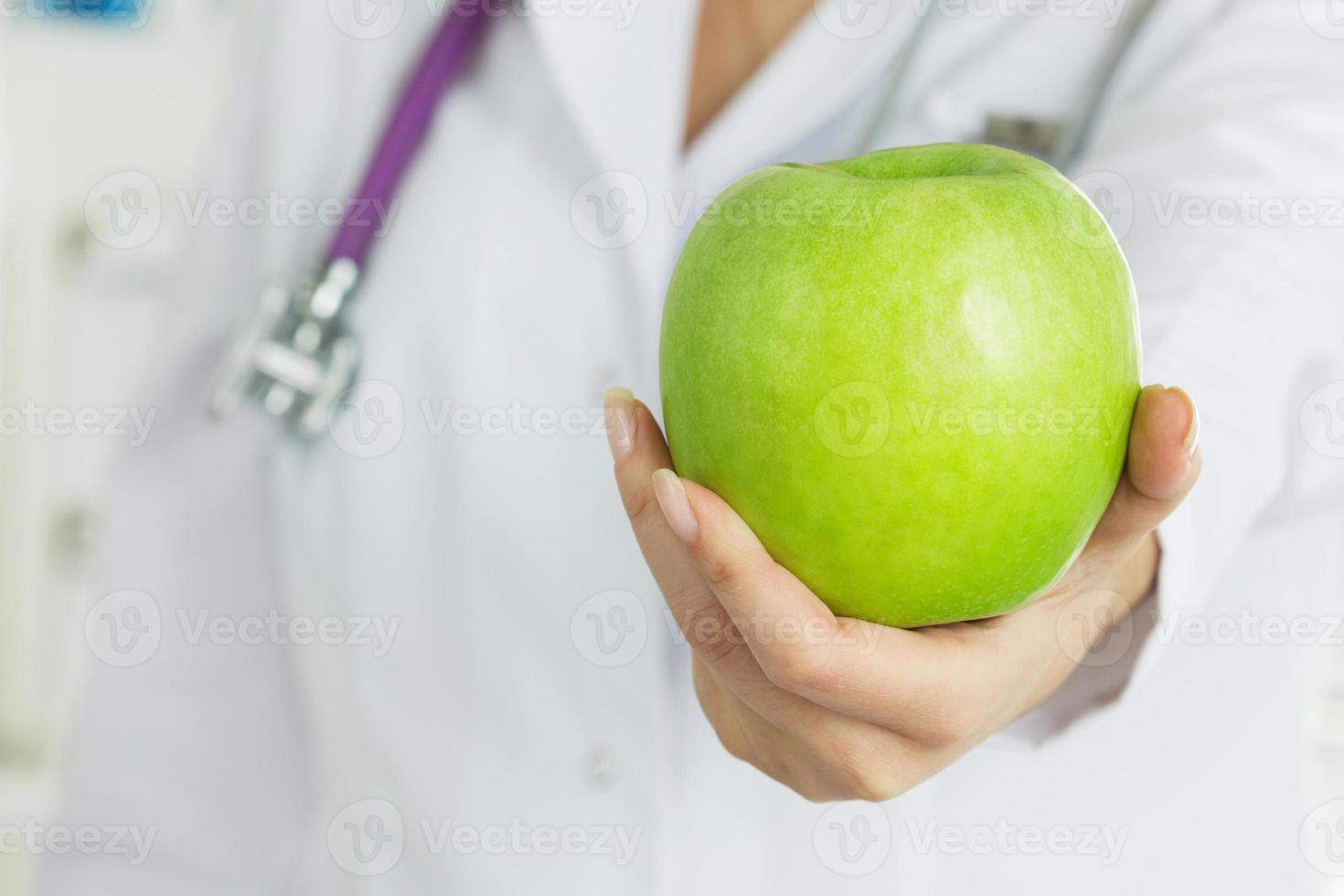 Ärztin, die frischen grünen Apfel anbietet foto