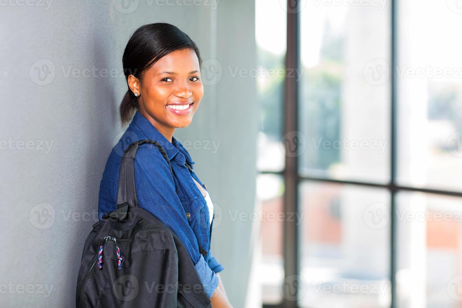 afrikanische Studentin, die sich gegen eine Wand lehnt foto