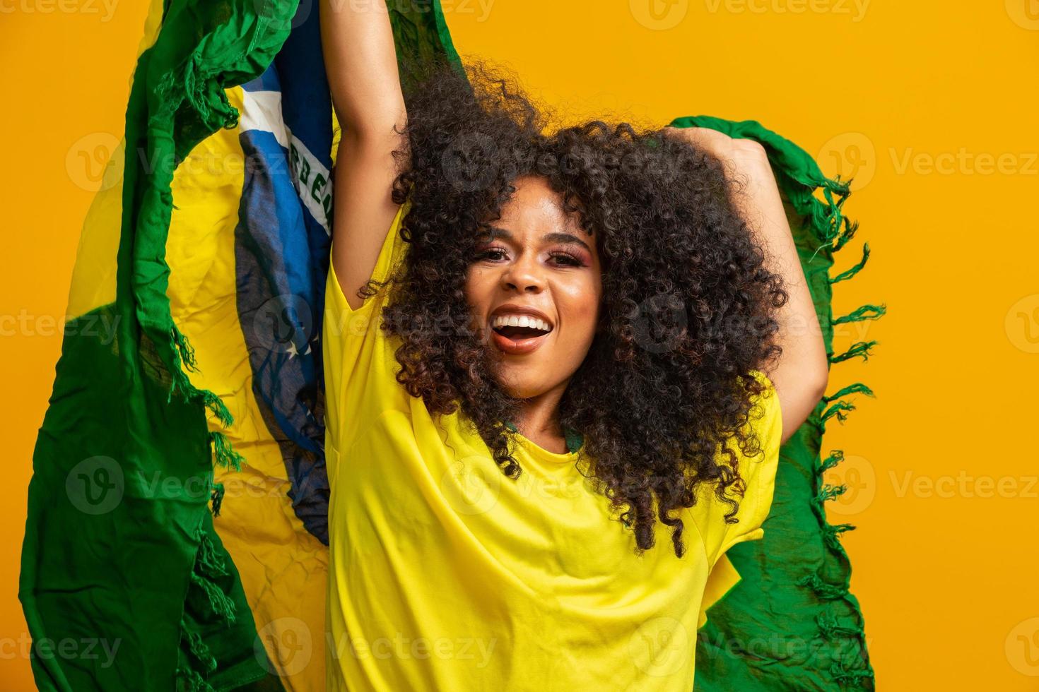 Afro-Mädchen jubelt der brasilianischen Lieblingsmannschaft zu und hält die Nationalflagge auf gelbem Hintergrund. foto