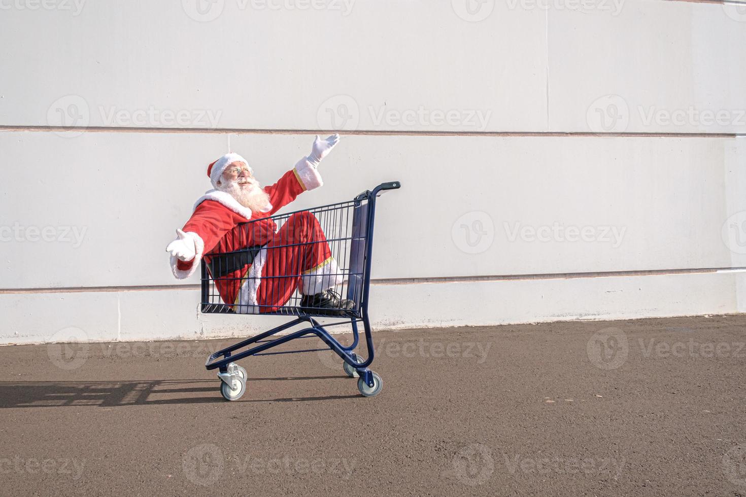 Supermarktwagen mit Weihnachtsmann im Inneren. einkaufen für weihnachtskonzept. foto