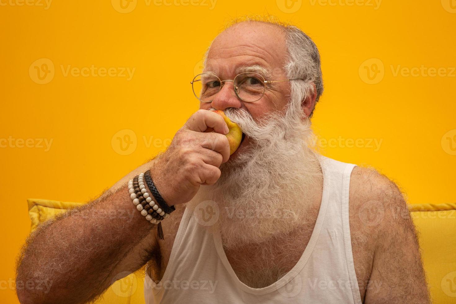 Porträt eines bärtigen Mannes, der kurz davor steht, einen Apfel zu essen. Senior, der einen Apfel hat. foto