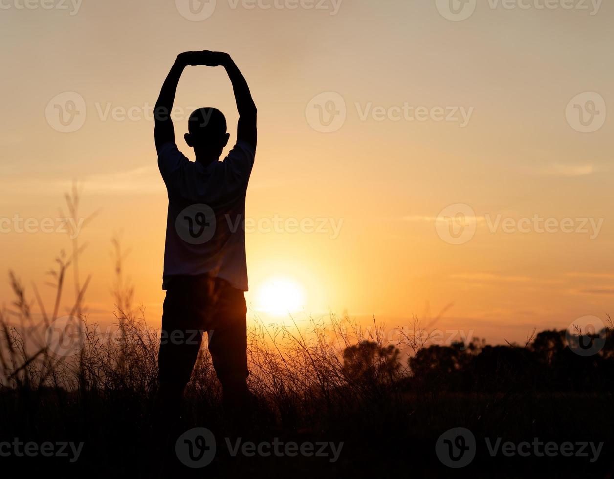 Silhouette des Sonnenuntergangs mit dem Rücken des Mannes, der den Körper streckt. foto