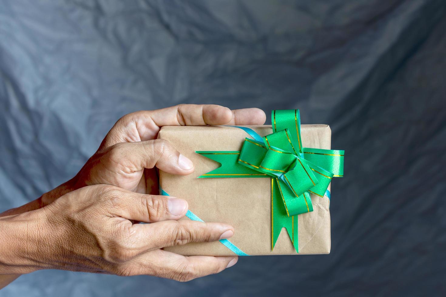 Hand, die Geschenkbox und Fliege als Hintergrund hält. foto