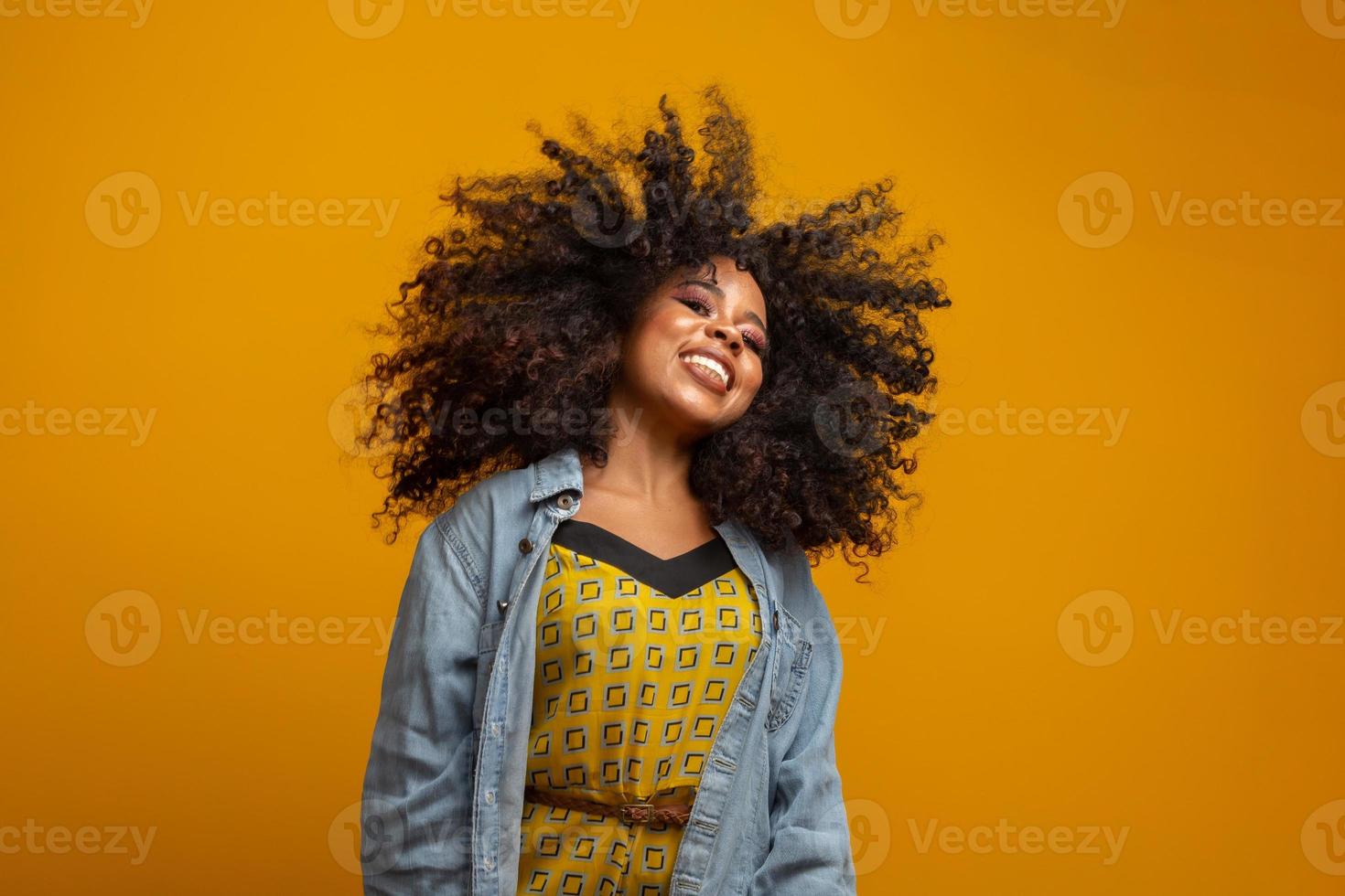 Schönheitsporträt einer afroamerikanischen Frau mit Afro-Frisur und Glamour-Make-up. brasilianische Frau. gemischtrassig. Lockige haare. Frisur. gelber Hintergrund. foto