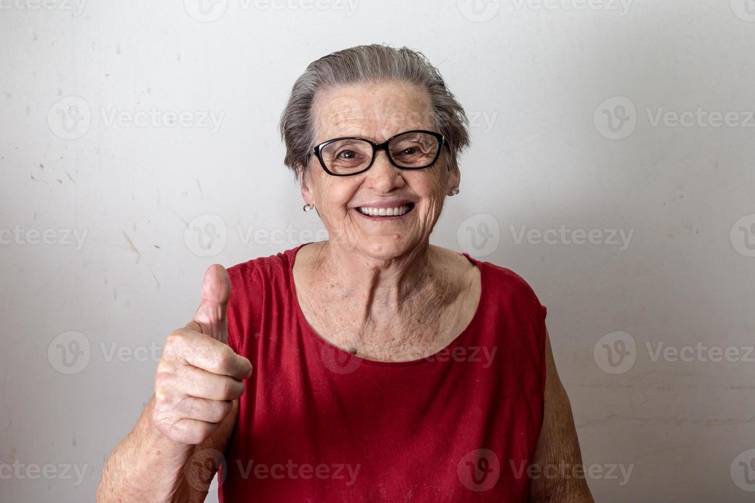 schöne alte Frau mit zwei Daumen nach oben. fröhlicher kaukasischer Senior, der zwei Daumen nach oben auf weißem Hintergrund zeigt. foto