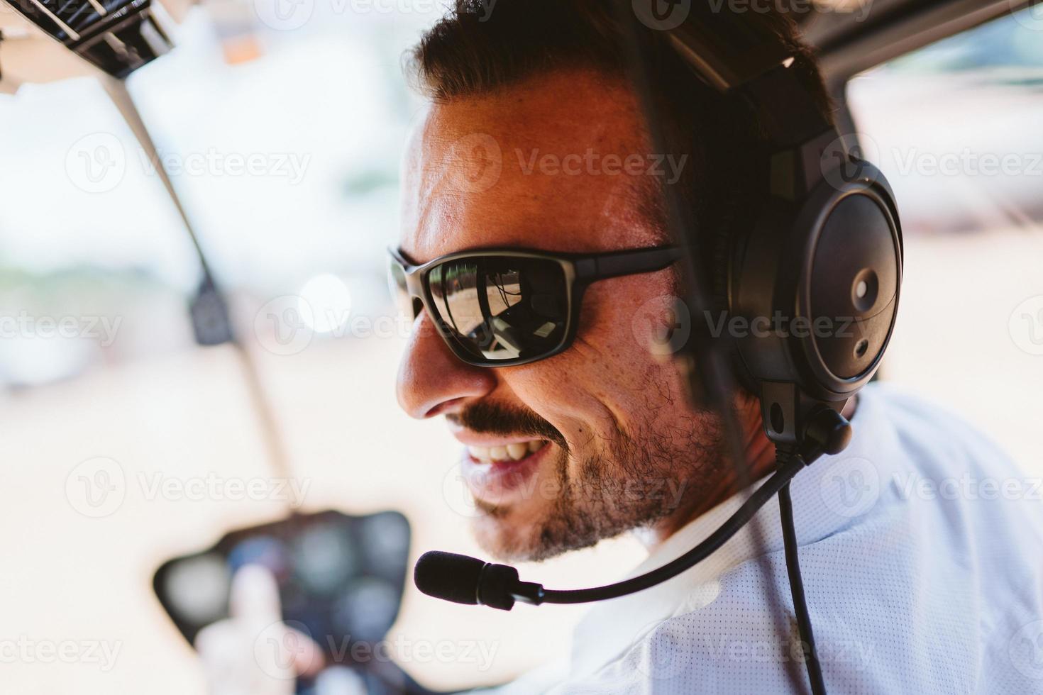 Pilot mit Headset, der Kontrollen in einem privaten Hubschrauber einleitet. Hubschrauberpilot sitzt im Cockpit. lateinischer Mann. foto