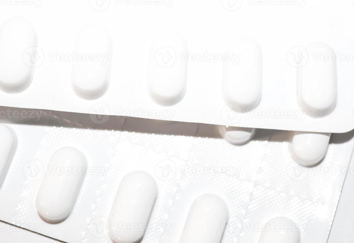 apotheke drogeriekonzept. Packungen mit weißen Pillen, die in Blisterpackungen verpackt sind, mit Kopienraum isoliert auf weißem Hintergrund. Fokus auf Vordergrund, weiches Bokeh. foto