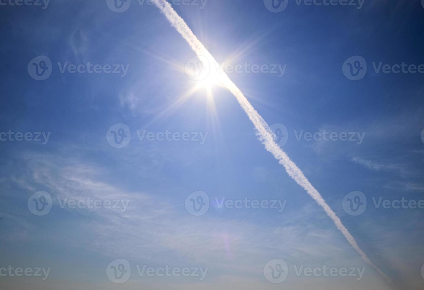 Flugzeug-Kondensstreifen am blauen Himmel zwischen einigen Wolken foto