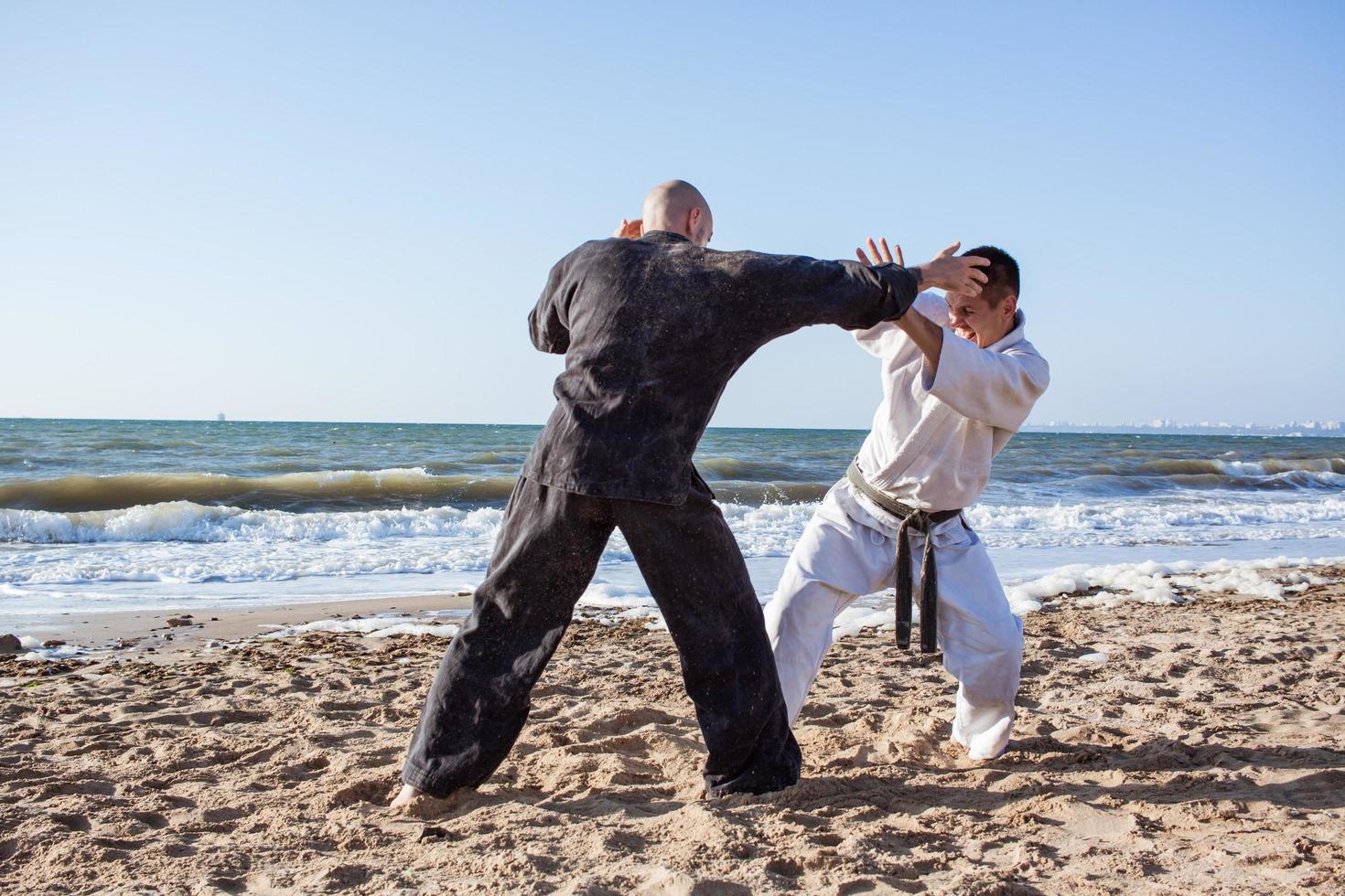 Karate-Kämpfer kämpfen morgens am Strand-Boxring foto