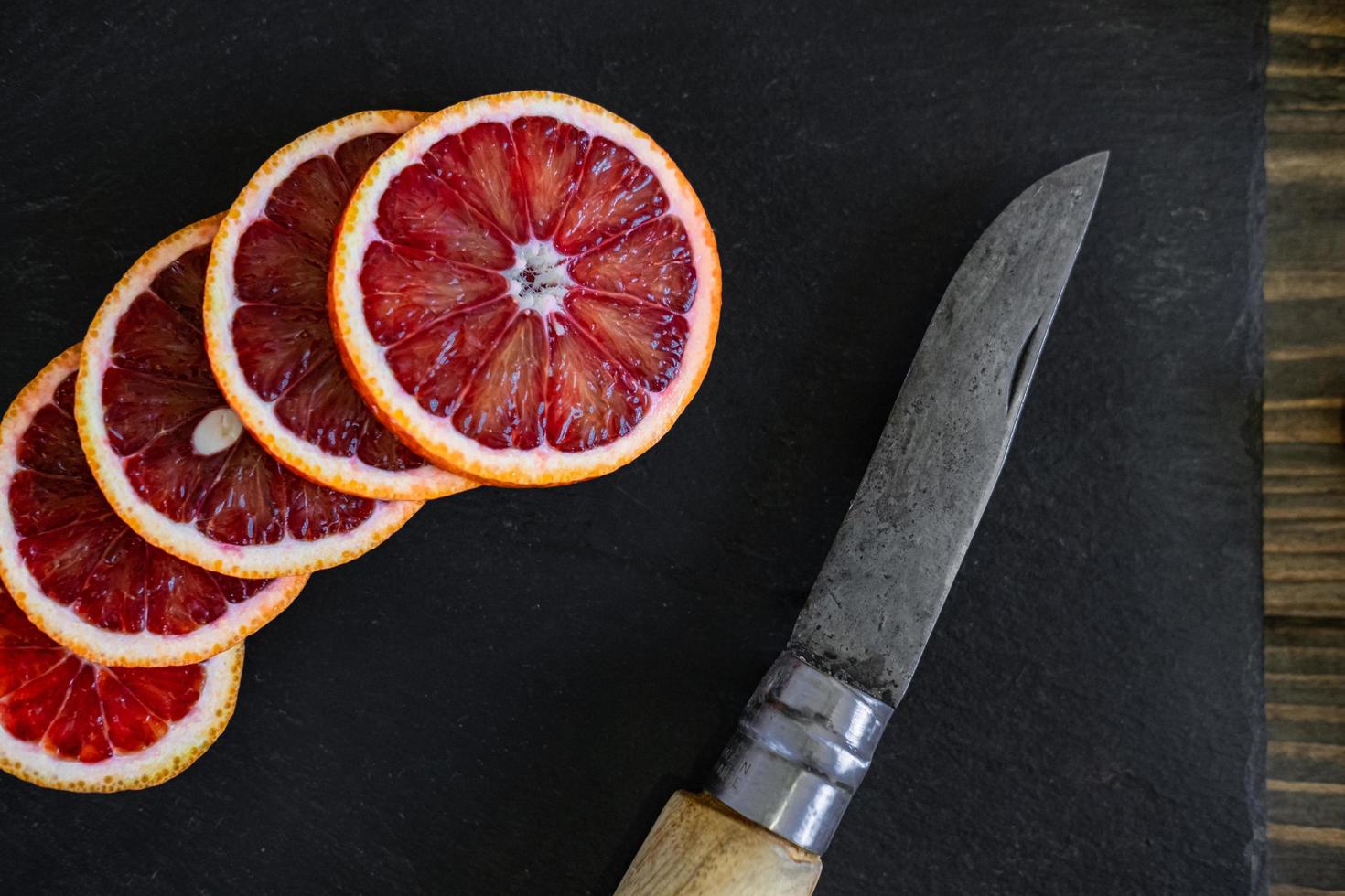 in Scheiben geschnittene sizilianische oder blutige Orangen auf schwarzem Schieferhintergrund foto