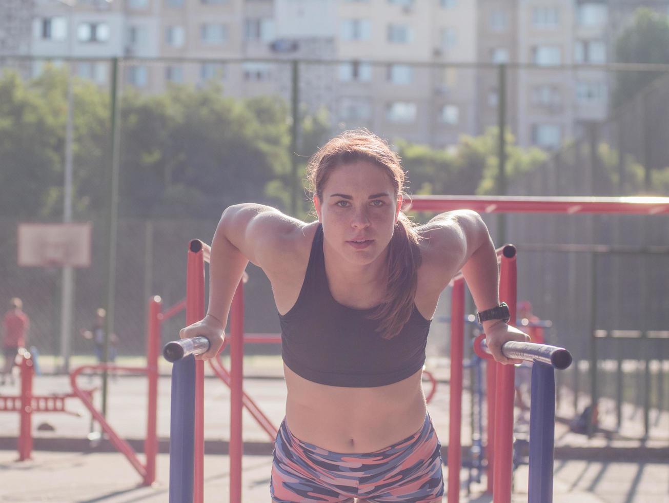 Junge starke Frau, die im Sommer im Freien trainiert, weibliche Profisportlerin macht Übungen im Park foto