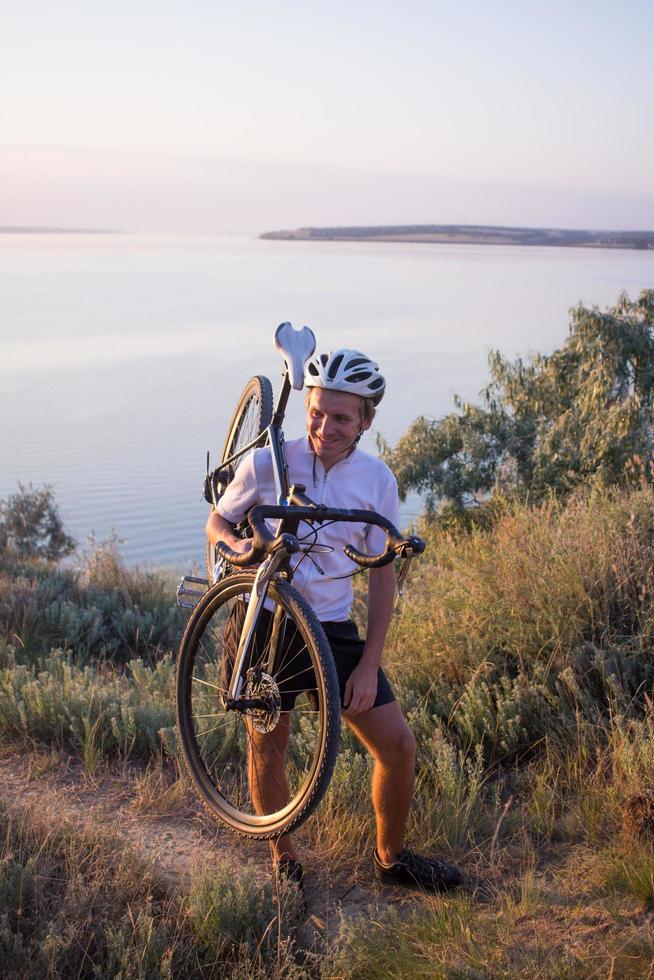 Fahrradfahrer auf professionellem Cyclocross-Rad fahren bergab, Kiefern- und Seehintergrund foto