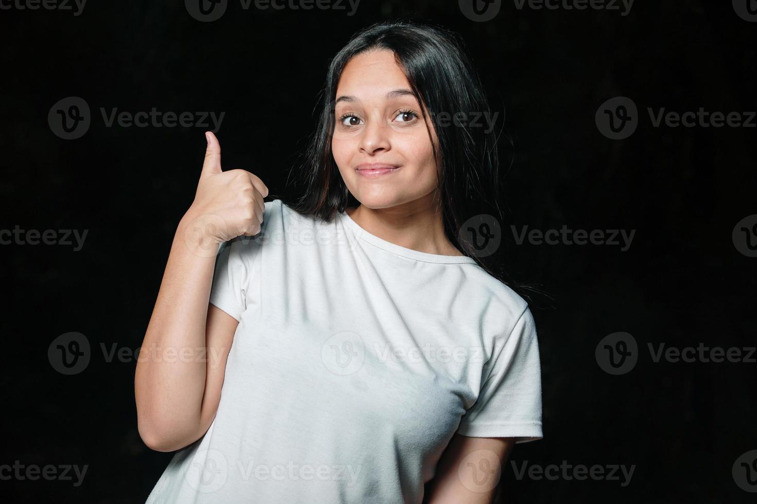 schöne Brünette Teenager-Mädchen lächelnd zeigt Daumen nach oben. foto