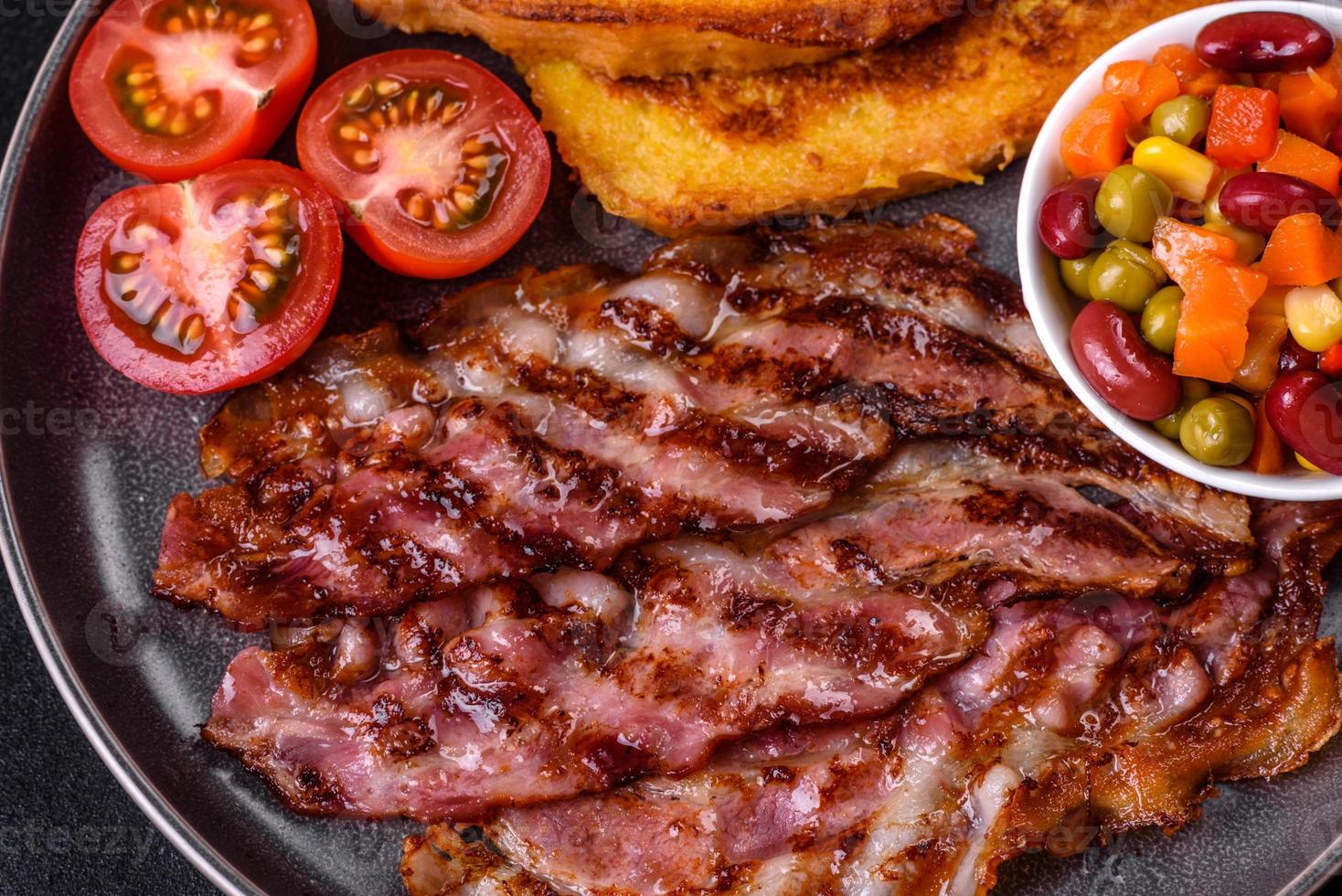 Köstlicher gegrillter Speck mit in Ei gebratenen Croutons mit Gewürzen, Salz, Gemüse und Kräutern foto