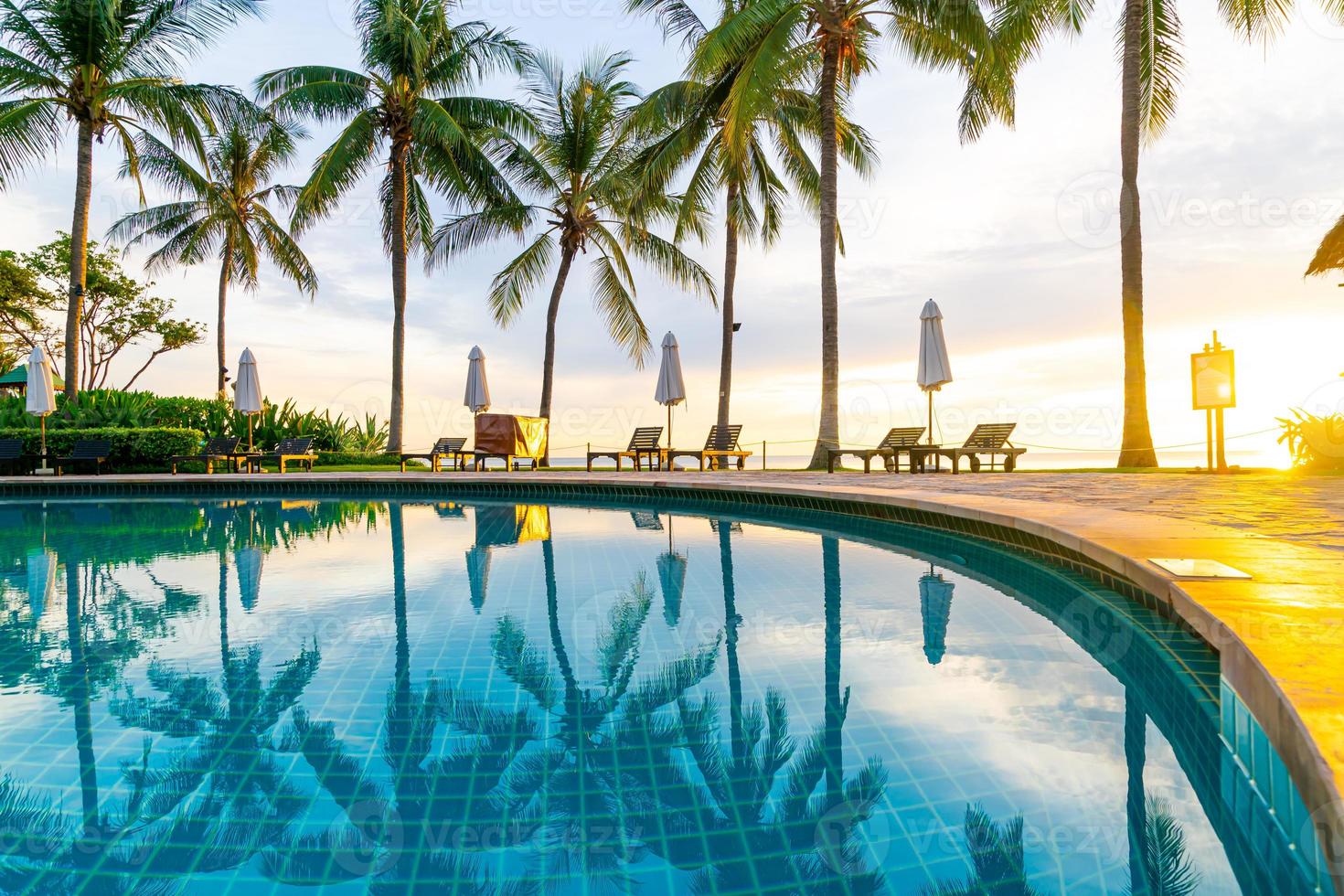 Sonnenschirm und Stuhl um den Pool im Hotelresort mit Sonnenaufgang am Morgen? foto