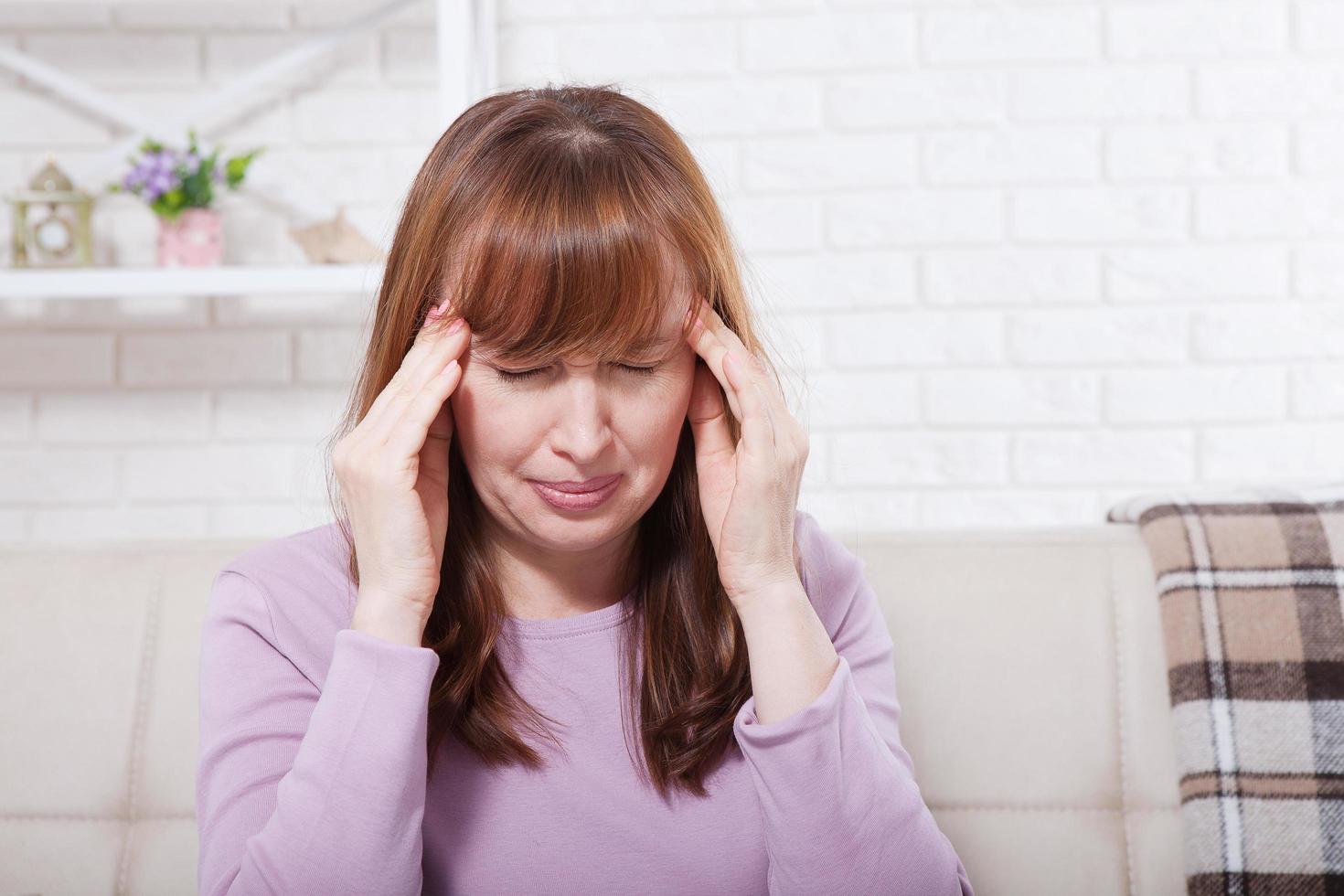 brünette frau mittleren alters, die kopfschmerzen im hintergrund hat. Wechseljahre und Stress. Depression. Platz kopieren und verspotten foto