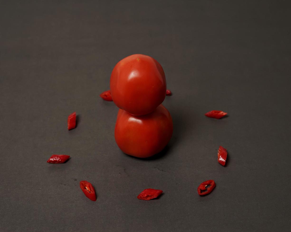 Die Kombination aus frischen Tomaten, roten Chilis und Eiern bildet ein lächelndes Gesicht. servierfertige Kochzutaten. Fokusunschärfe, Hintergrundinspiration. schwarze und rote Farbkombination. foto