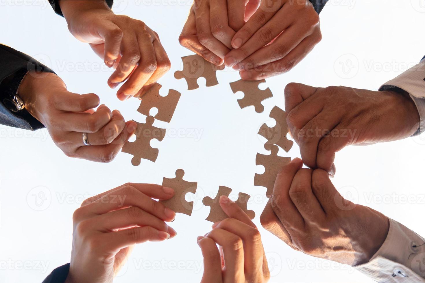 Die Hand eines Geschäftsmannes, der ein Papierpuzzle hält und das Puzzle gemeinsam löst. Das Geschäftsteam setzt ein Puzzle zusammen. eine Unternehmensgruppe, die die Puzzleteile zusammenfügen möchte foto
