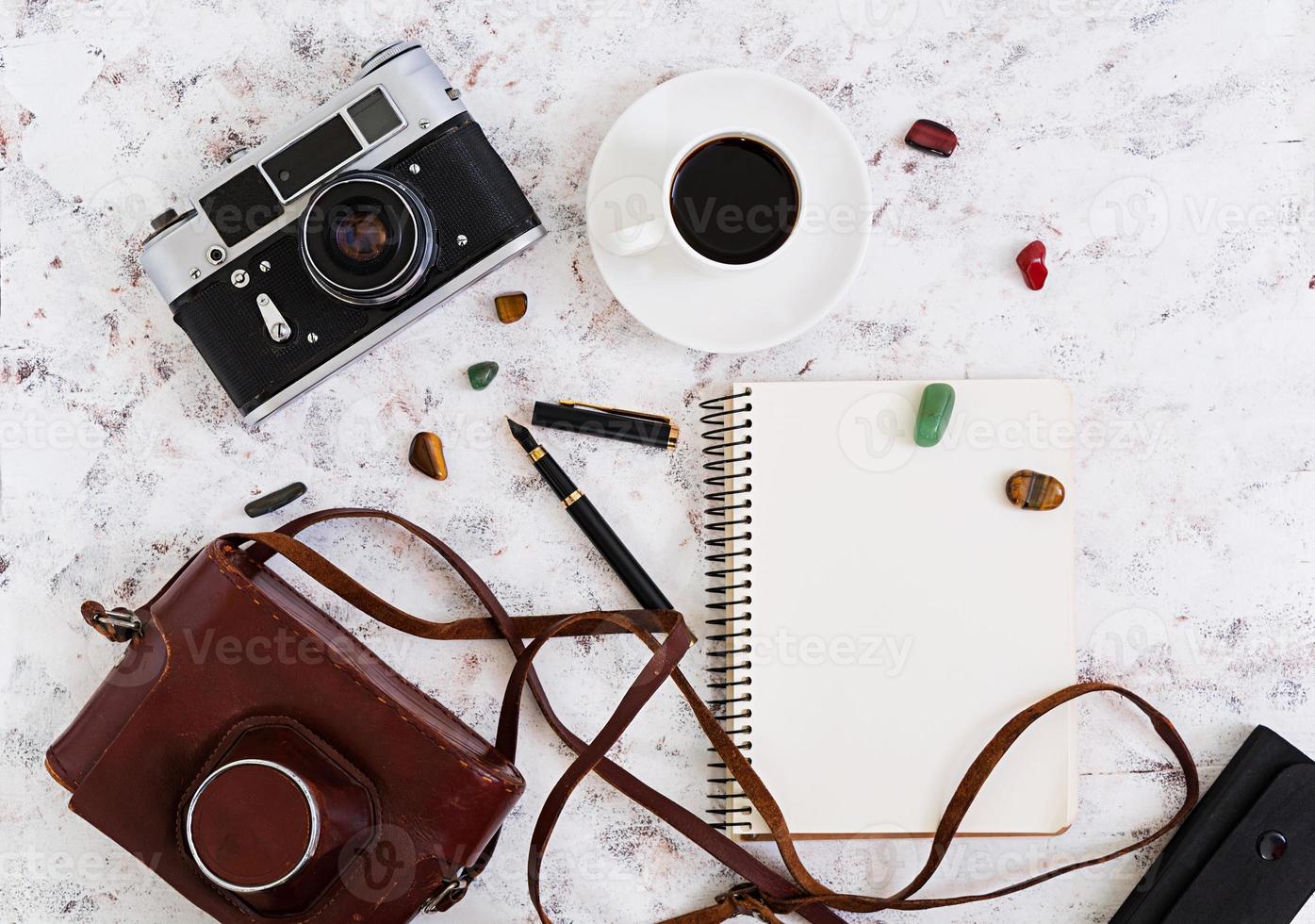 flache Lage, Draufsicht Bürotisch Schreibtisch. schreibtischarbeitsplatz mit retro-kamera, tagebuch, stift, brille, fall, tasse kaffee auf weißem hintergrund. foto