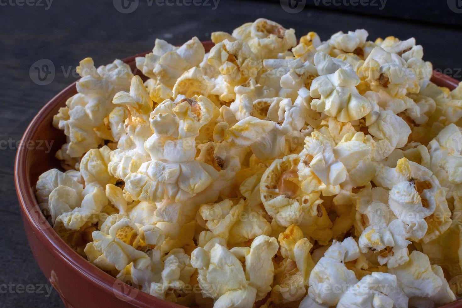 schüssel mit popcorn mit aufgerissenem beutel, der flach herausragt foto