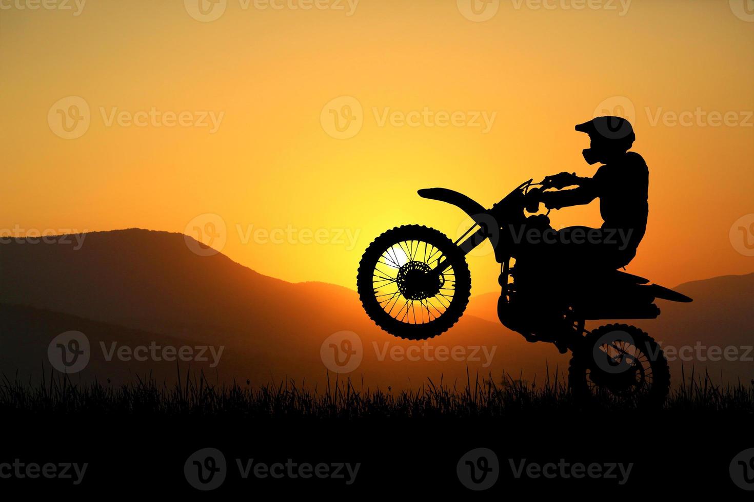 Silhouette eines Motocross-Motorrads, das das Vorderrad anhebt. Abenteuer- und Aktionskonzepte foto