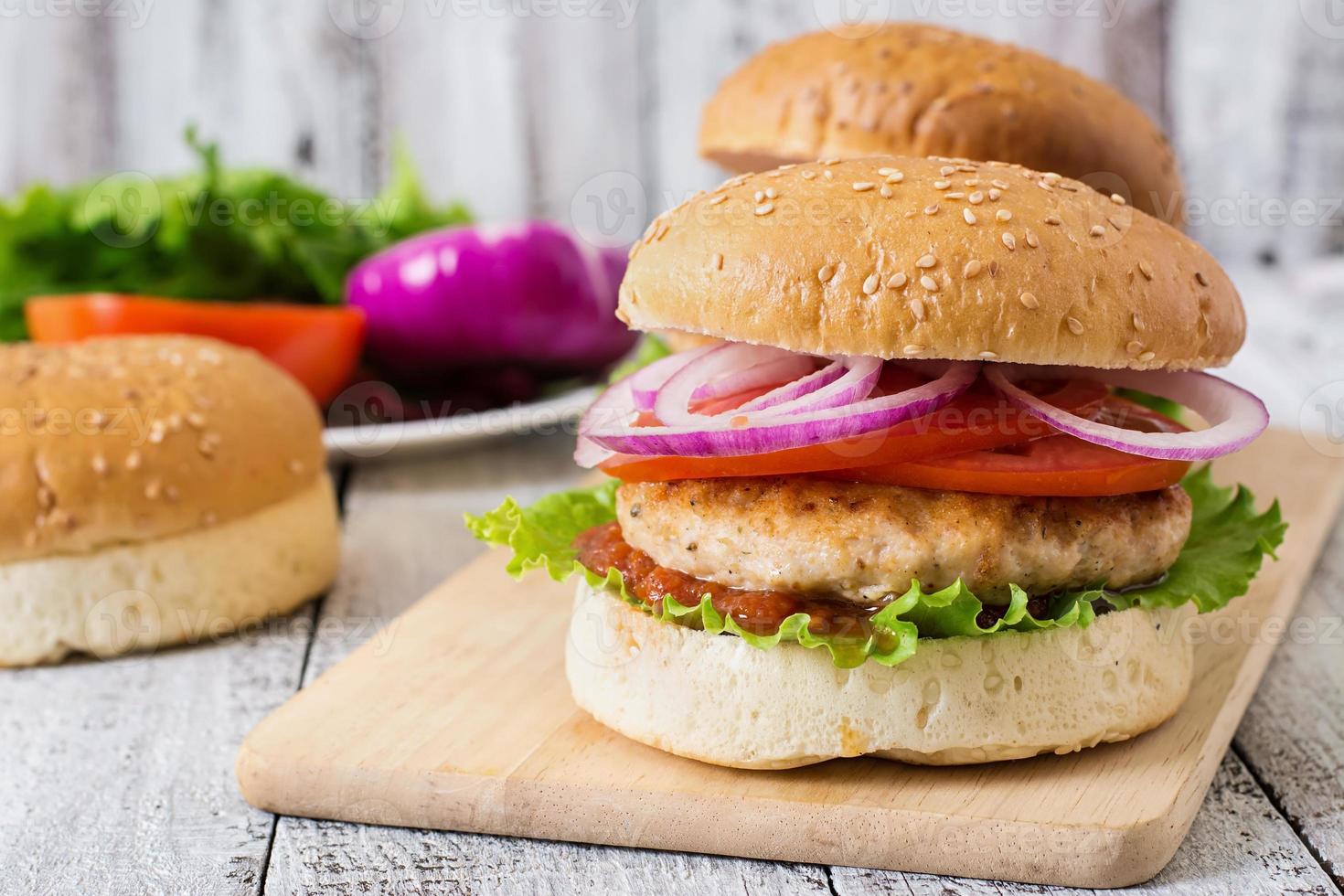 Sandwich mit Chicken Burger, Tomaten, roten Zwiebeln und Salat foto