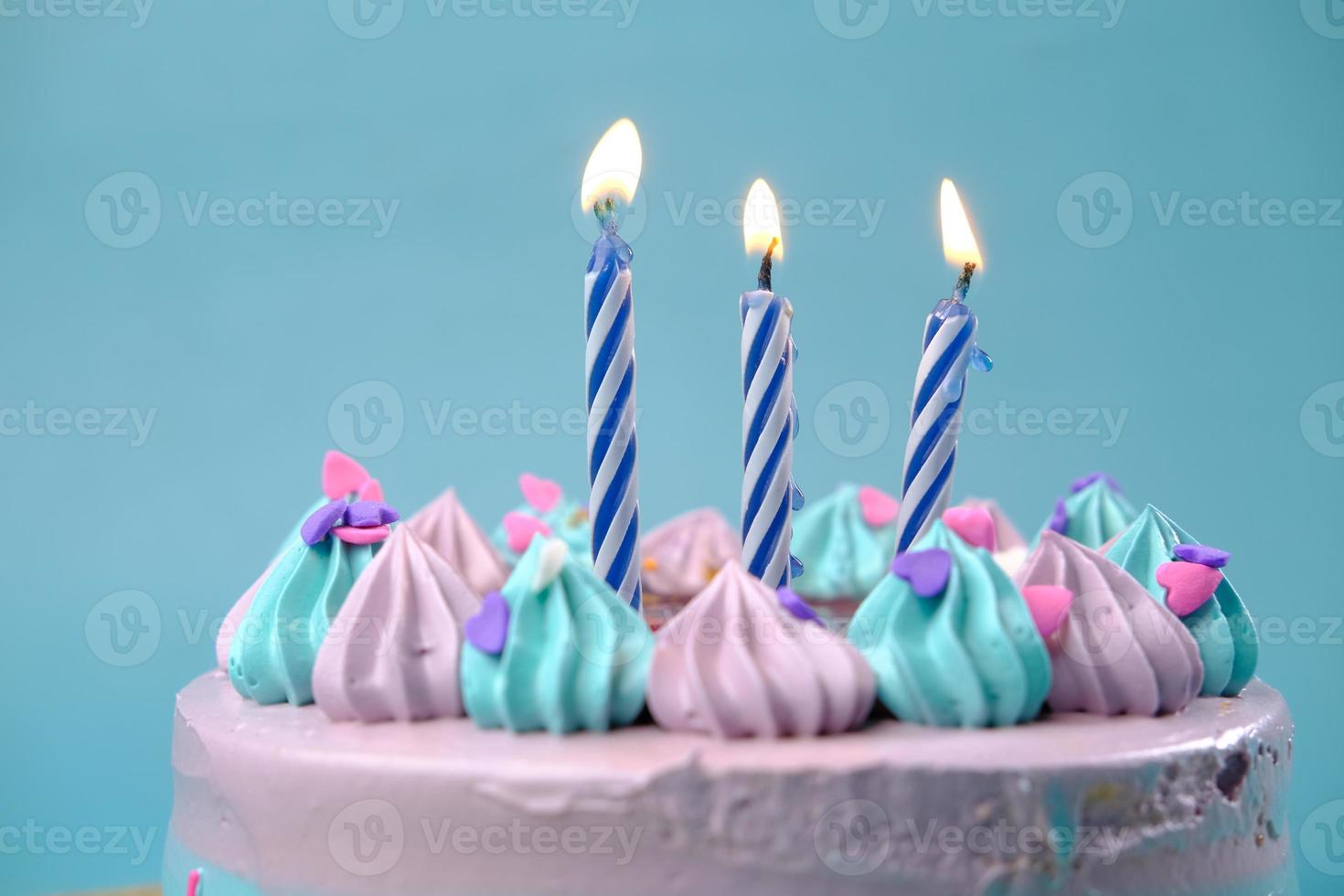 brennende Kerze auf einem Geburtstagskuchen auf farbigem Hintergrund foto