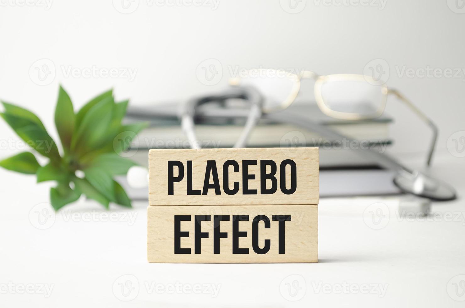 Placebo-Wort in Holzwürfeln auf einem weißen Tisch mit Medikamenten und einem Stethoskop geschrieben foto