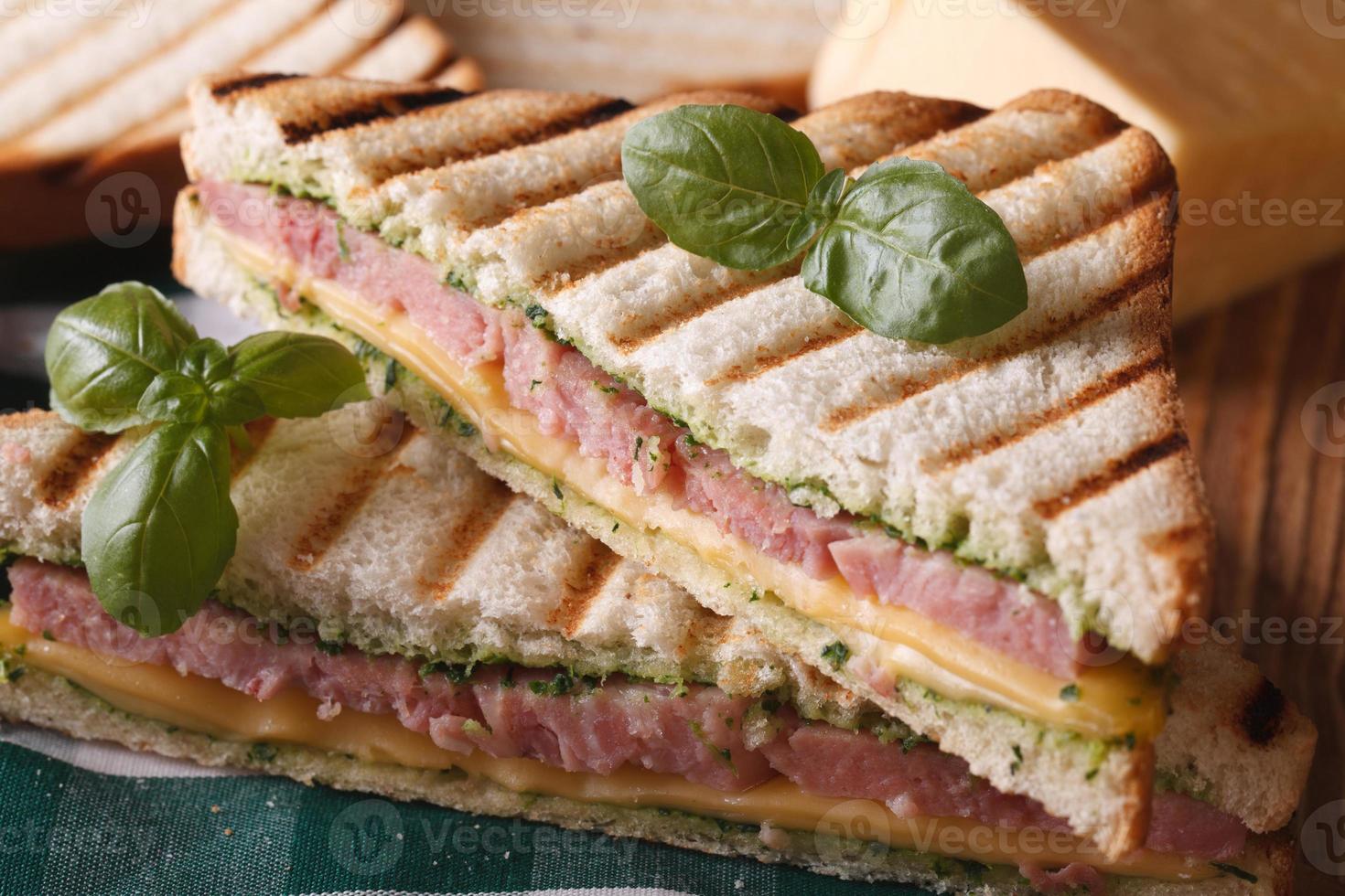Gegrilltes Sandwich mit Schinken, Käse und Basilikum Nahaufnahme foto