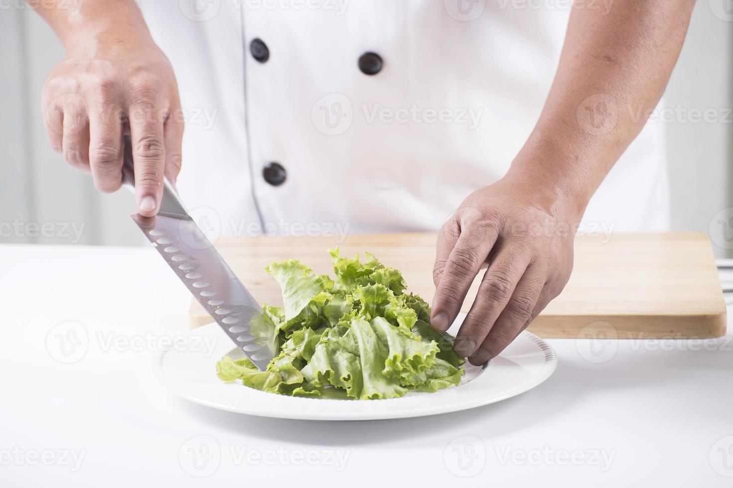 Koch, der Salat schneidet foto