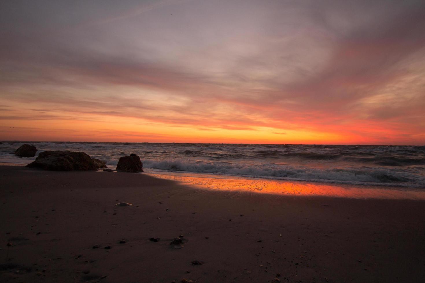 schöne meereslandschaft in der sonnenaufgangszeit, bunter rosa und orangefarbener himmel und sturm im meer. foto