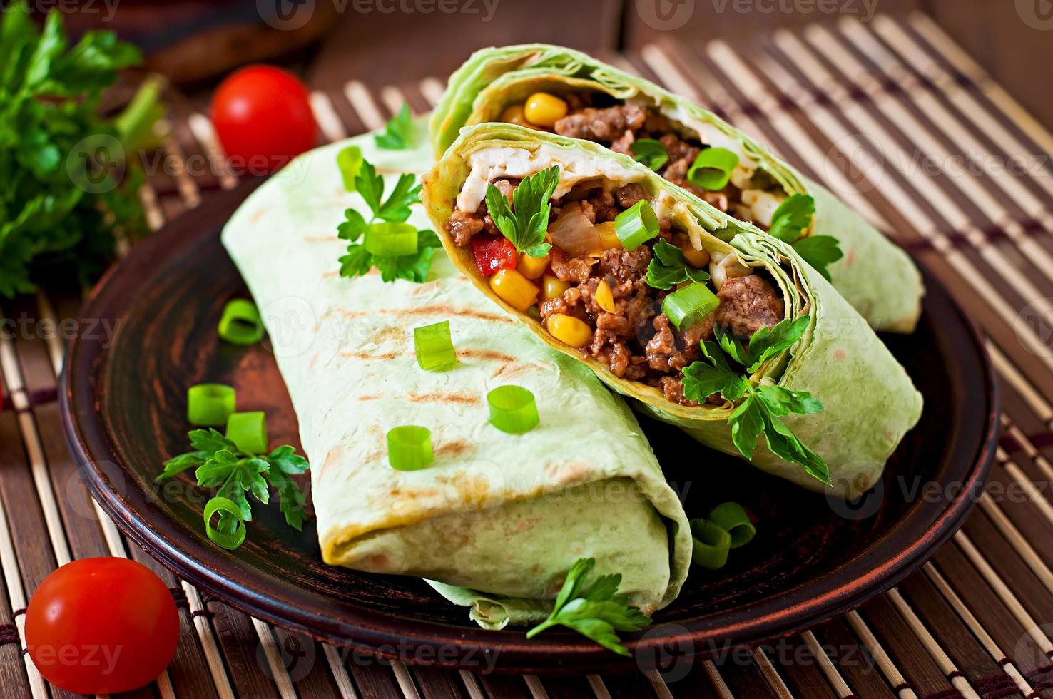 Burritos wickelt mit Hackfleisch und Gemüse auf einem hölzernen Hintergrund ein foto