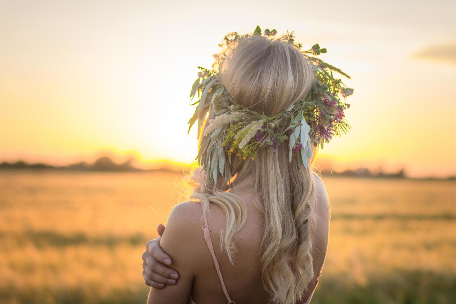 Porträts von jungen Frauen, die sich während des Sonnenuntergangs im Weizenfeld gut amüsieren, Dame im Kopfblumenkranz während foto