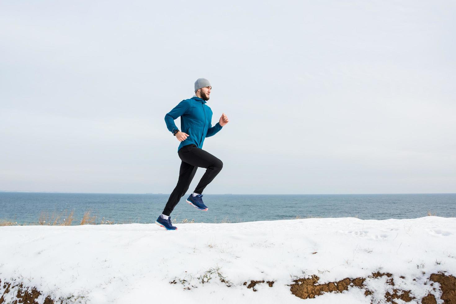 junger männlicher läufer, der im winter draußen trainiert, mann läuft auf dem schnee foto