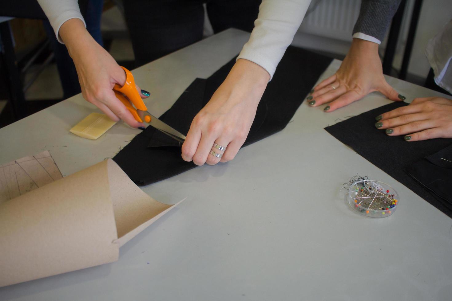 Näherin bei der Arbeit auf dem Tisch, Schneiderfrau arbeitet im Studio mit Kleidung foto