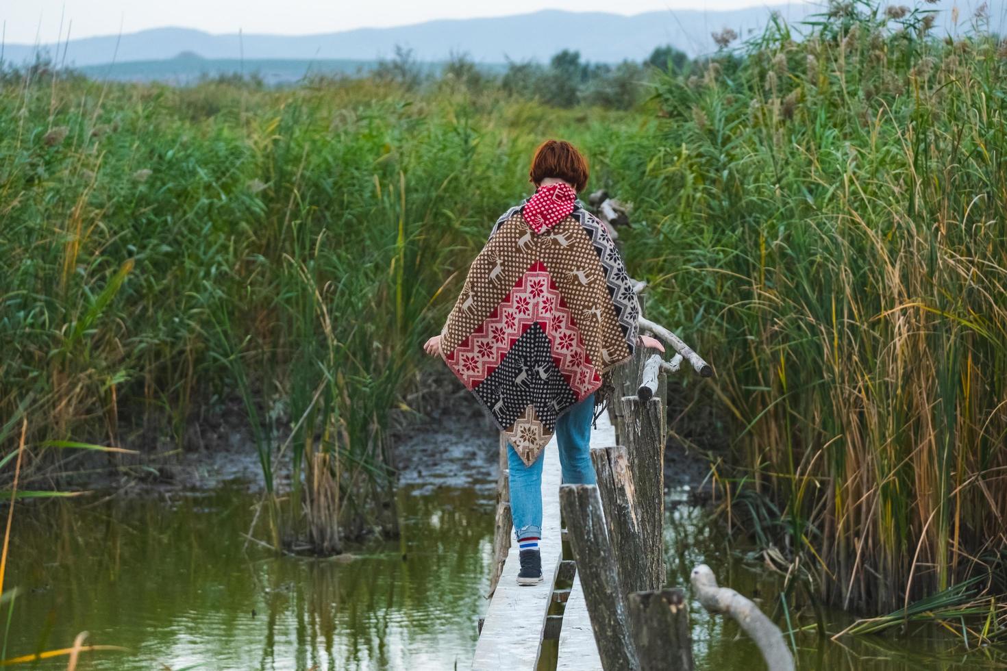 Junge Reisende in einem Poncho gehen im Freien auf Herbstfeldern foto