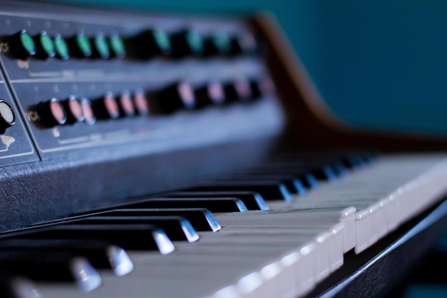 Alter Synthesizer mit farbenfrohen Schaltern auf blauem Hintergrund foto