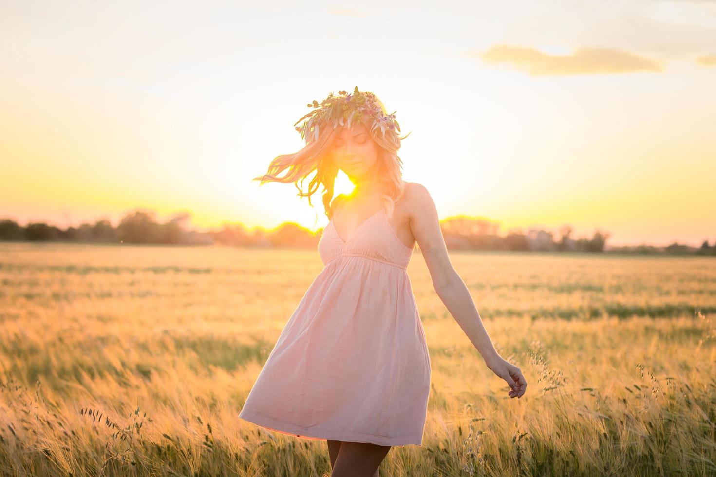 Porträts von jungen Frauen, die sich während des Sonnenuntergangs im Weizenfeld gut amüsieren, Dame im Kopfblumenkranz während foto