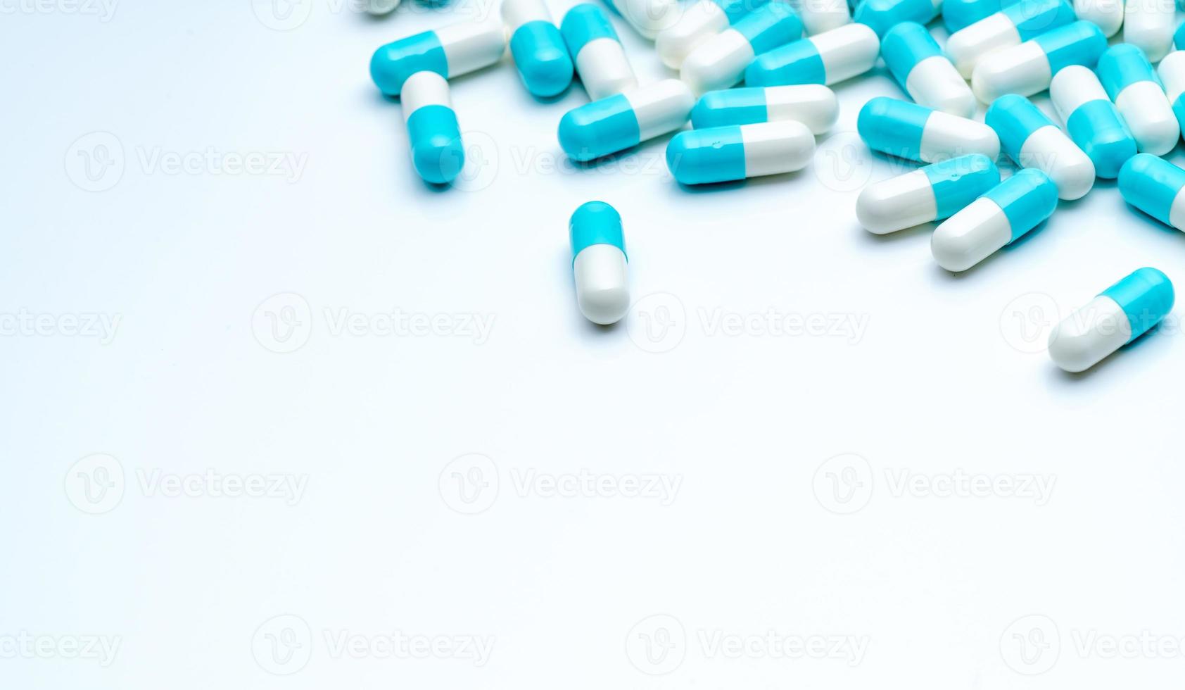 Blau-weiße Kapselpillen verteilen sich auf weißem Hintergrund mit Kopierraum. Pharmaindustrie. apotheke drogerie produkte. Pharmazie und Gesundheitshintergrund. Drogenkonsum im Krankenhaus. Gesundheitsbudget. foto