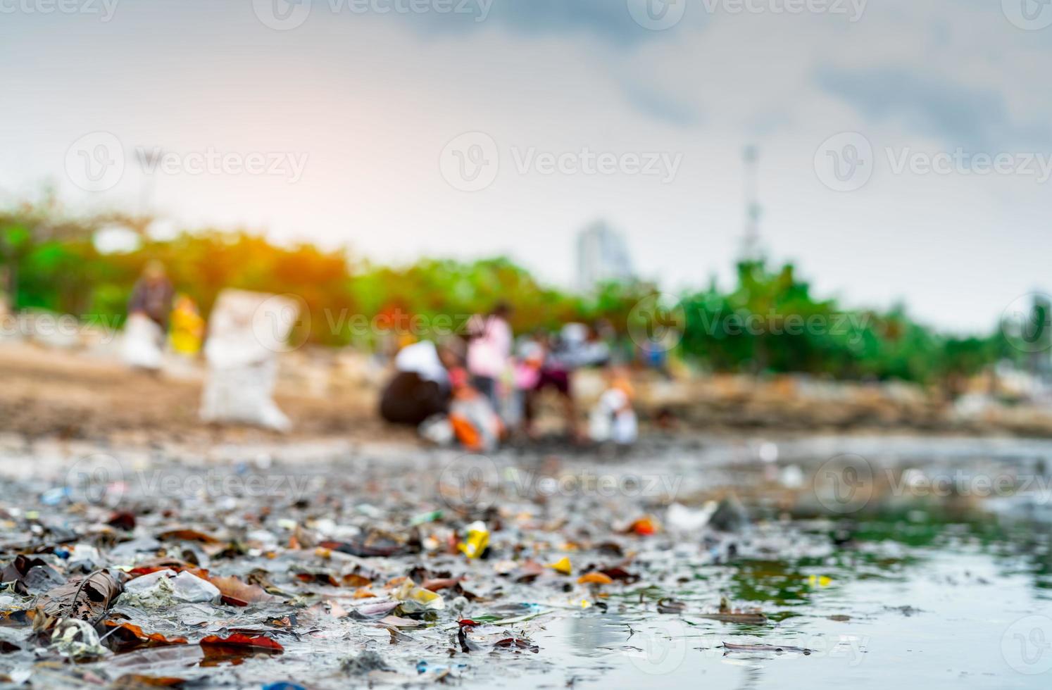 verschwommen von Freiwilligen, die Müll sammeln. Umweltverschmutzung am Strand. Freiwillige reinigen den Strand. Müll am Strand aufräumen. Ölflecken am Strand. Ölaustritt ins Meer. foto