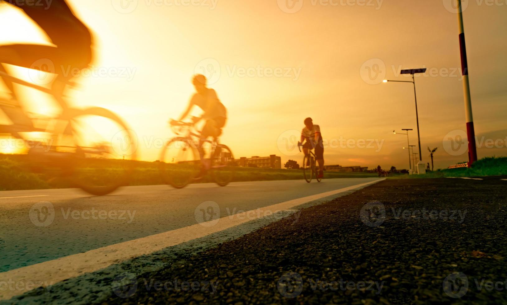 verwischen Sie Fotosportler fahren Fahrräder mit Geschwindigkeitsbewegung auf der Straße am Abend mit Sonnenunterganghimmel. Sommerübungen im Freien für ein gesundes und glückliches Leben. radfahrer, der mountainbike auf radweg fährt. Team. foto